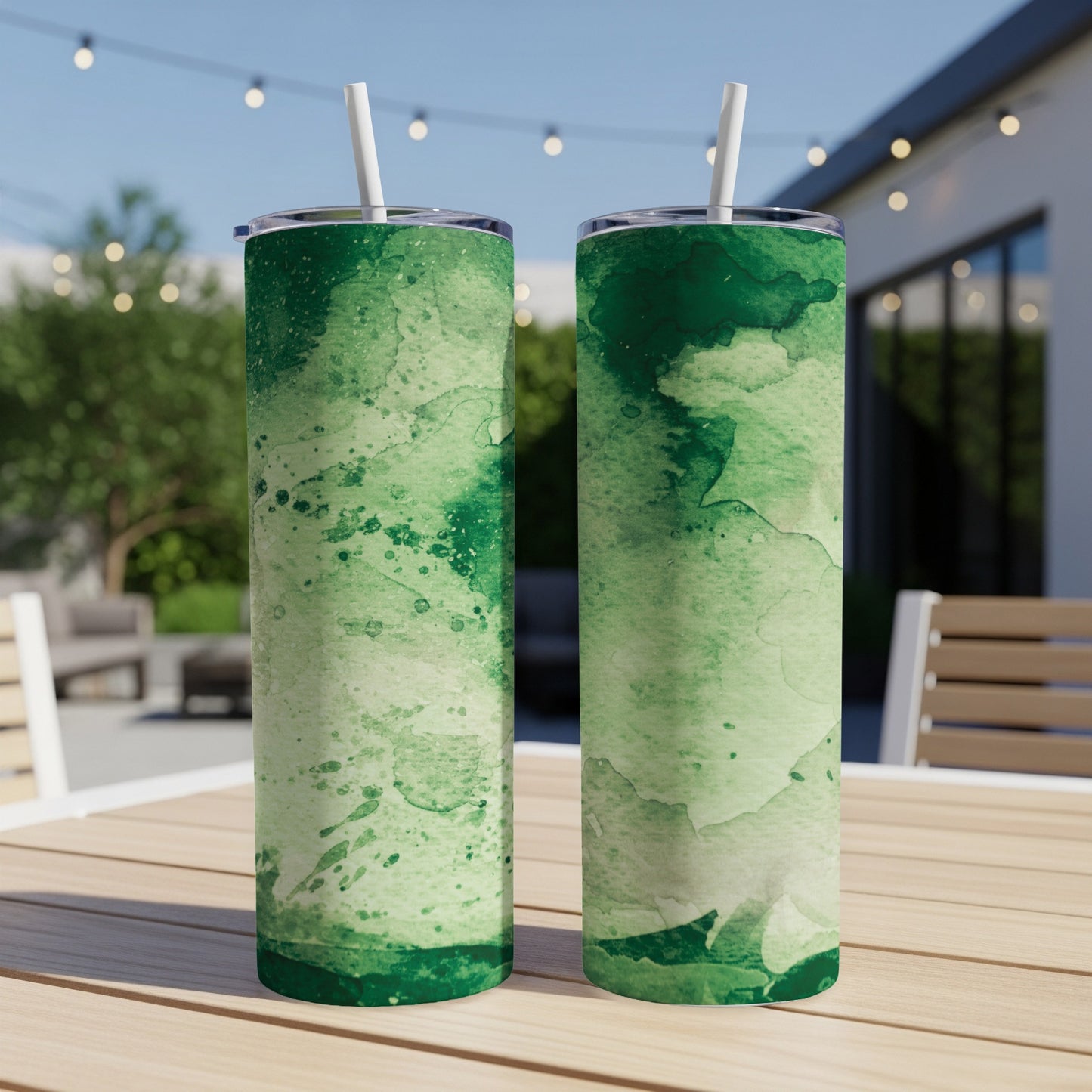 Two green watercolor print tumblers with straws on a wooden table.