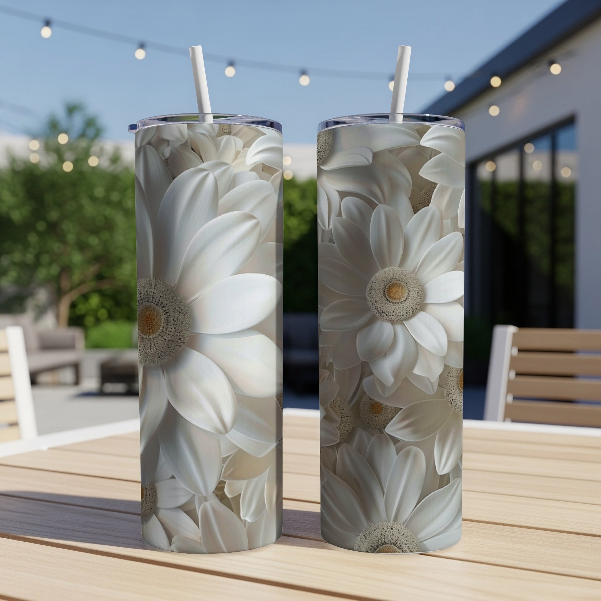 Two tall, floral-patterned tumblers with straws sit on a table outdoors.