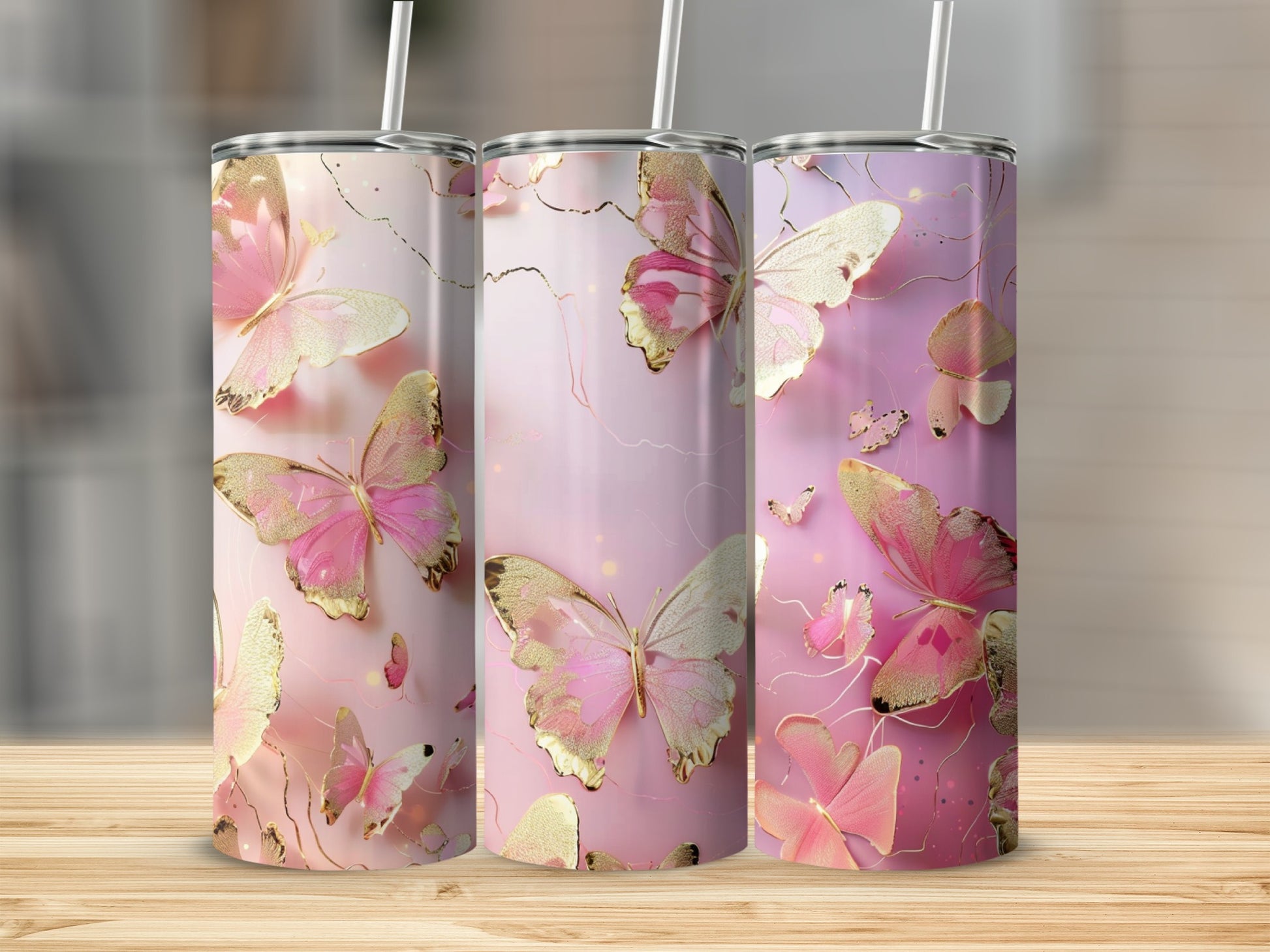 Three tumblers with pink and gold butterfly designs on a wooden surface.
