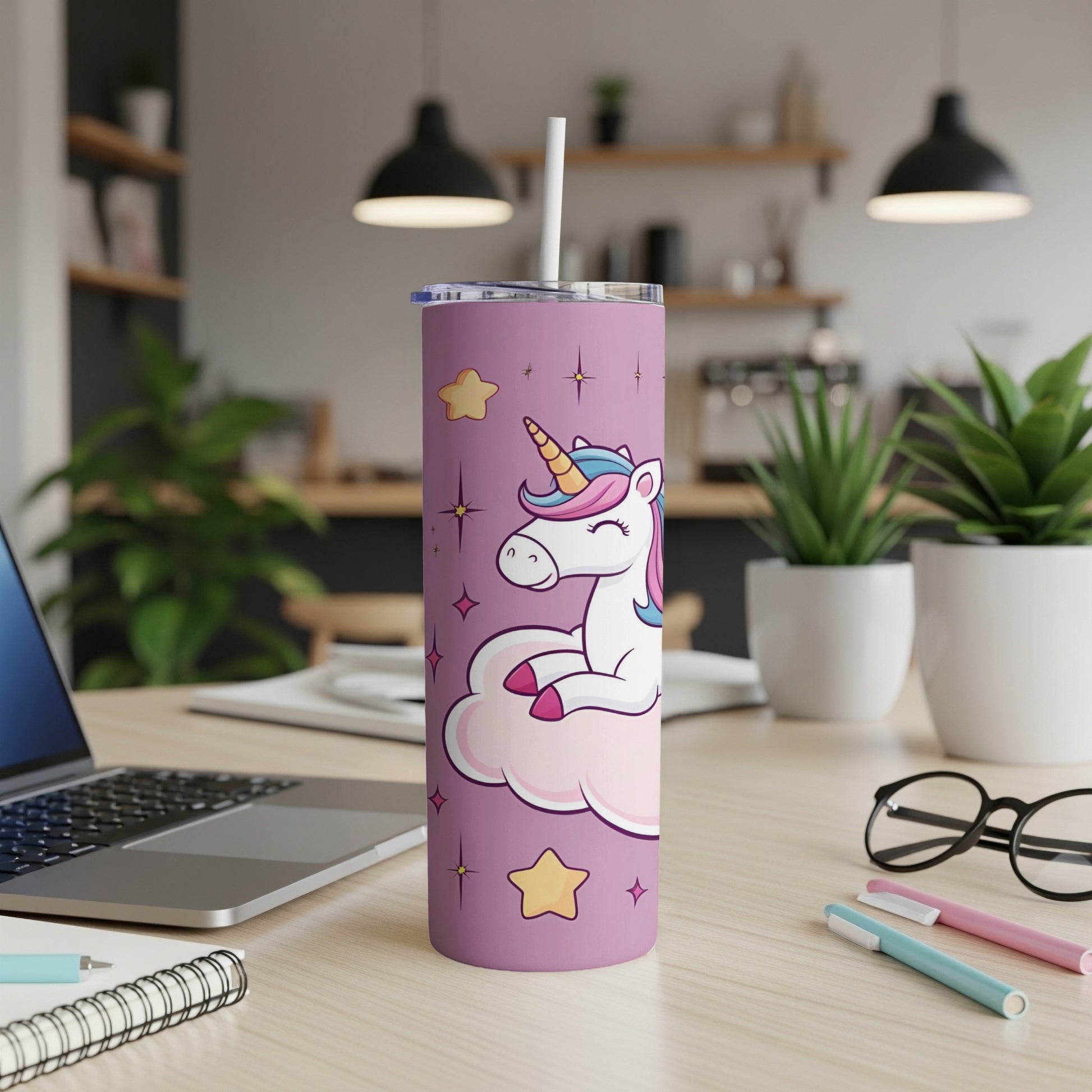 Purple tumbler with unicorn on a cloud, stars, and pens on desk.