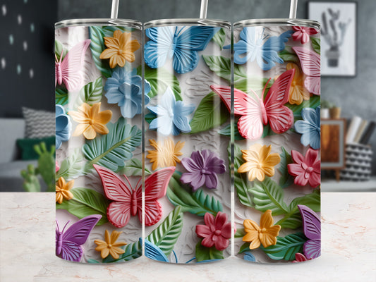 Three tumblers with raised butterflies and floral designs on a marble surface.