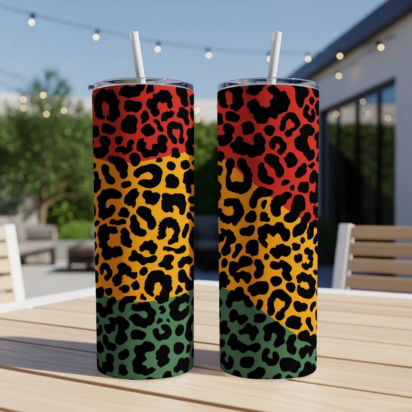 Two tall tumblers with leopard print in red, yellow, green, and black on a table.