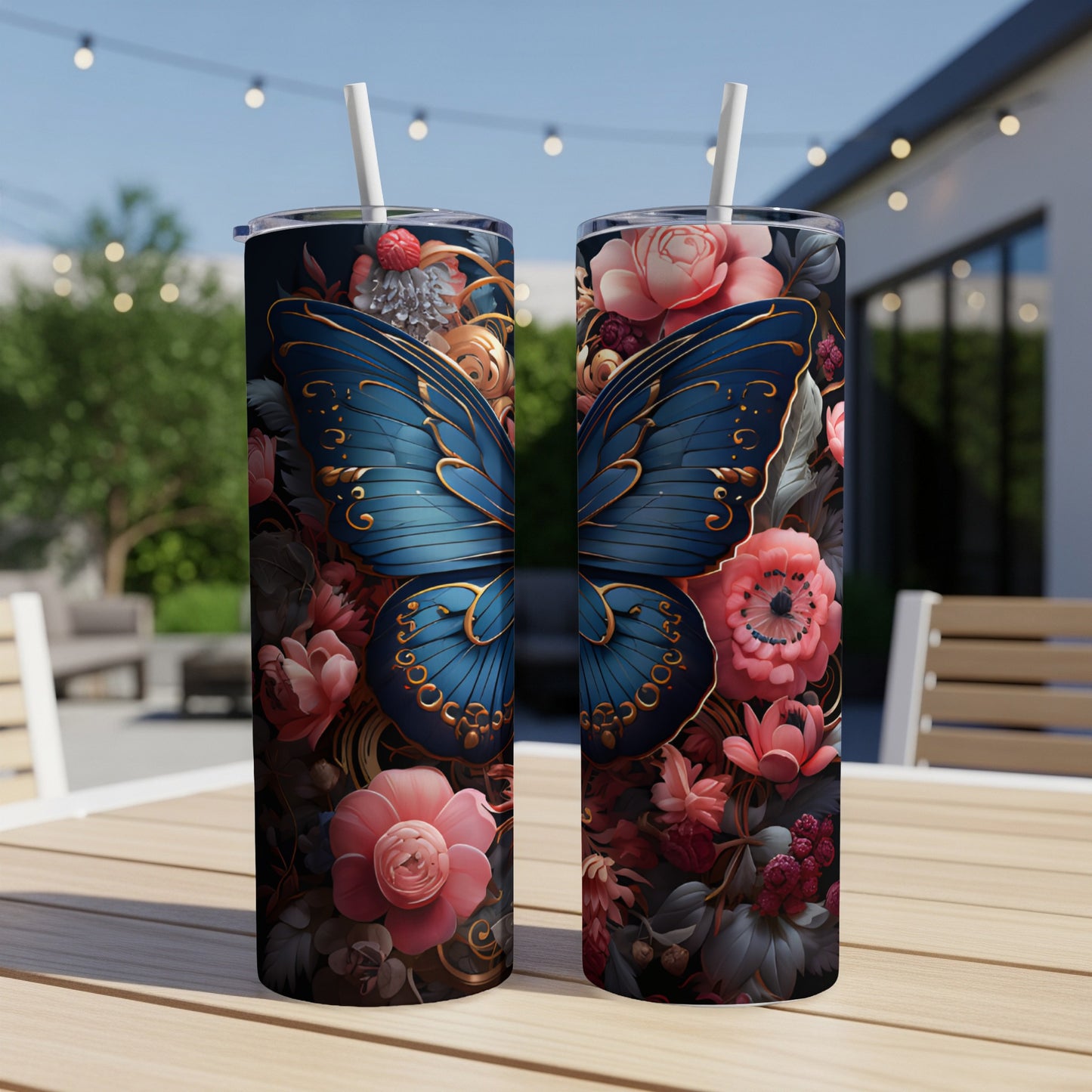Two tumblers with blue butterfly and floral designs sit on a wooden table outdoors.
