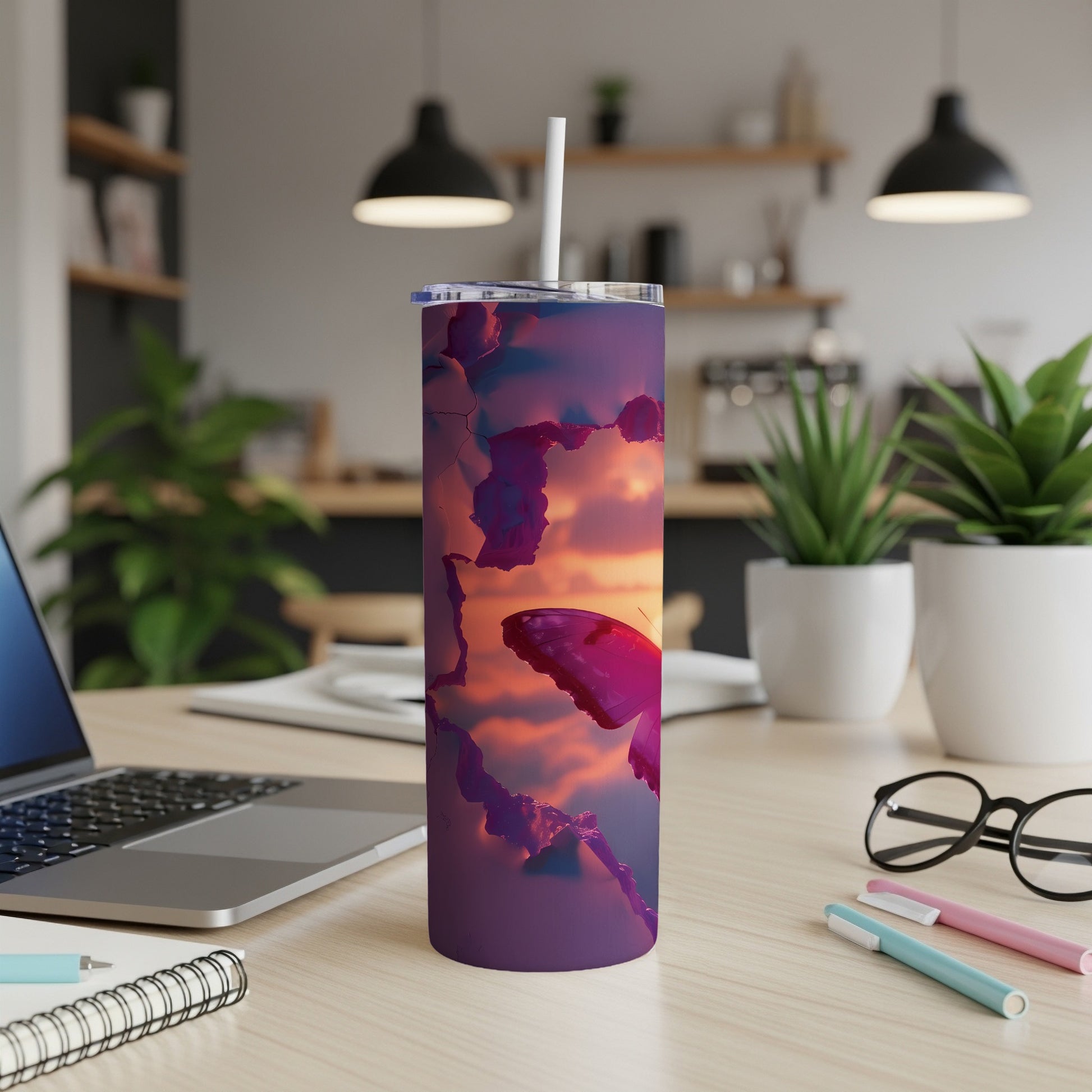 Purple tumbler with butterfly and sunset graphic, on a desk.