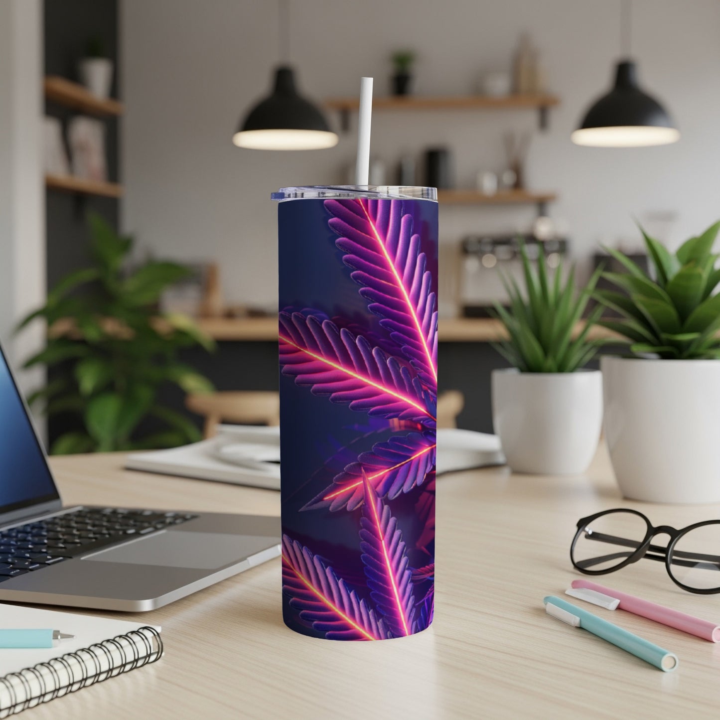 Neon marijuana leaf tumbler with straw on a desk.