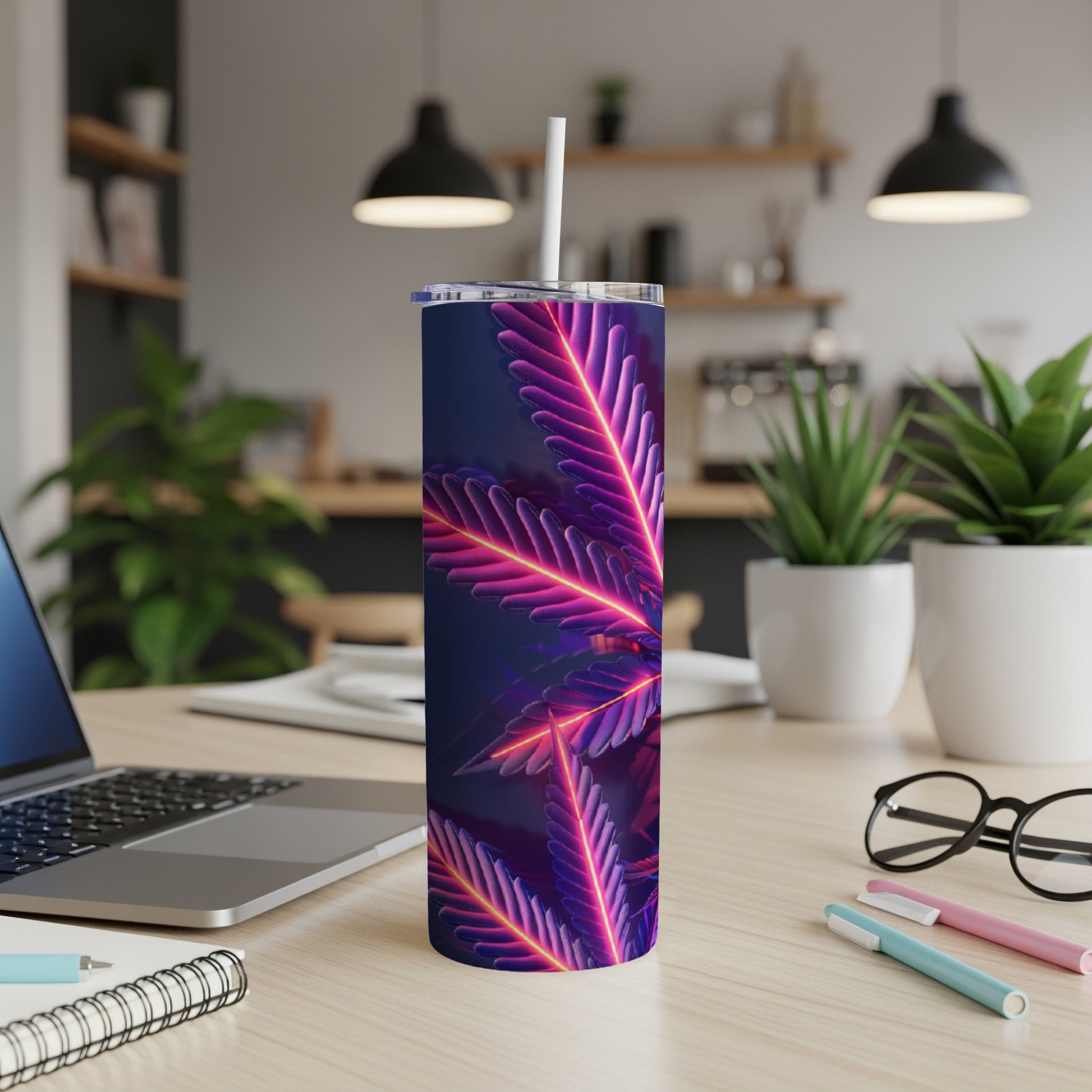 Neon marijuana leaf tumbler with straw on a desk.