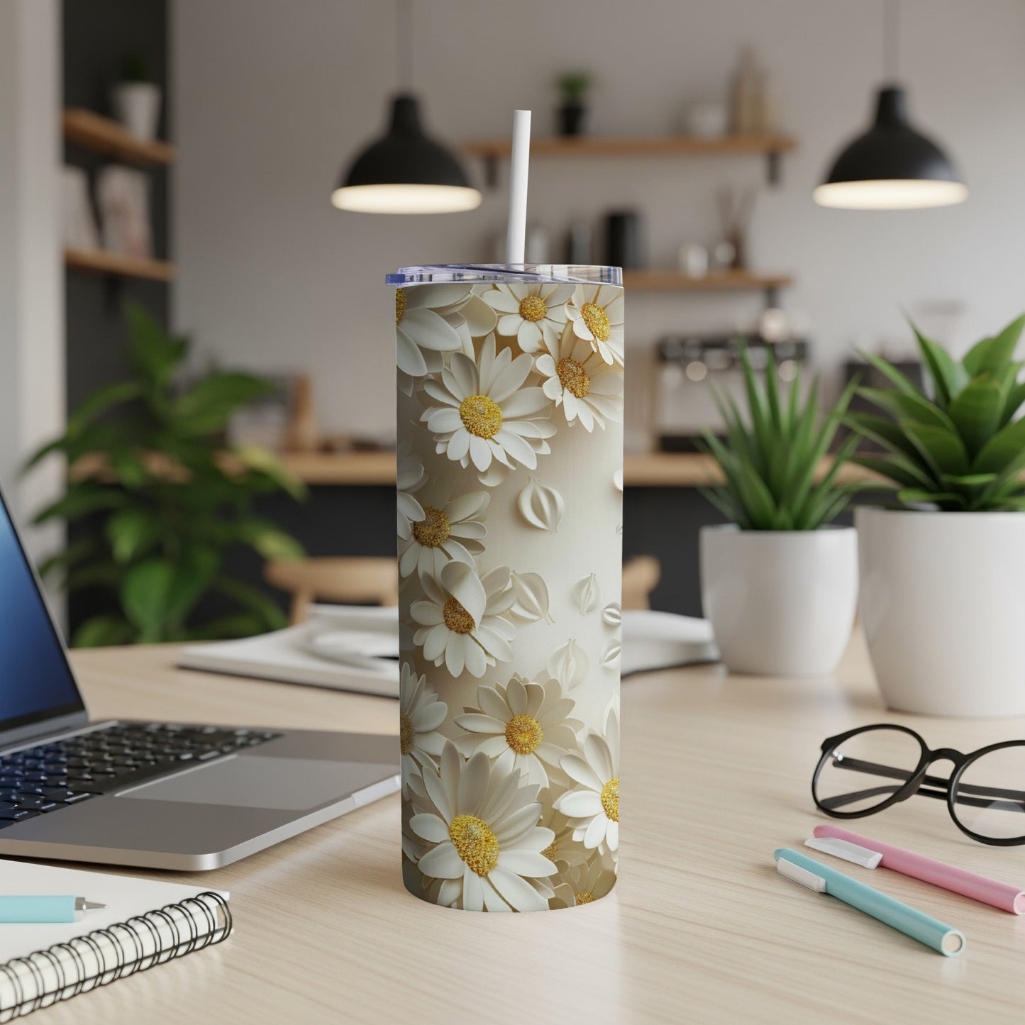 White floral patterned tumbler with straw on a wooden desk.