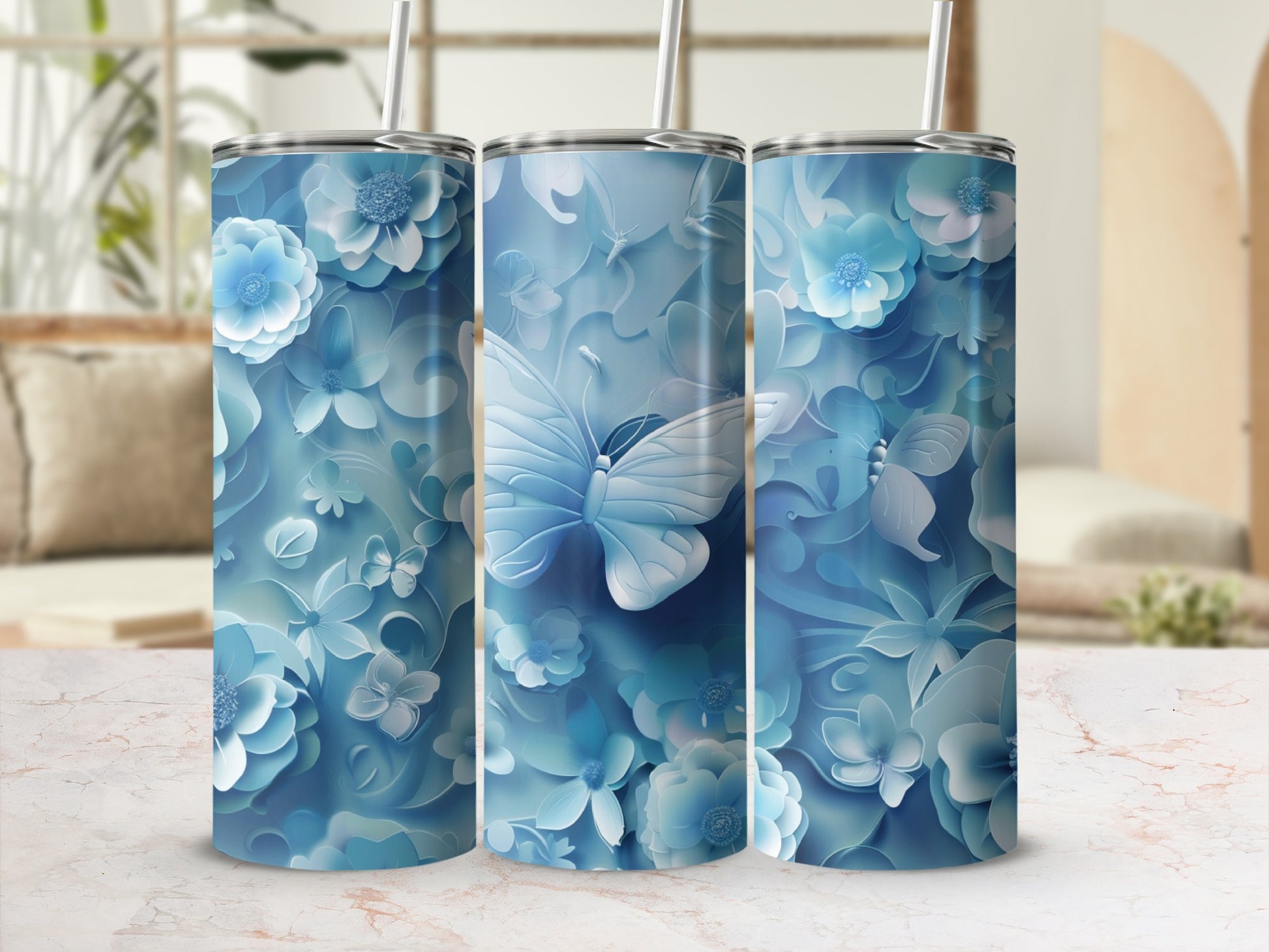 Three blue floral tumblers with butterfly designs on a light background.