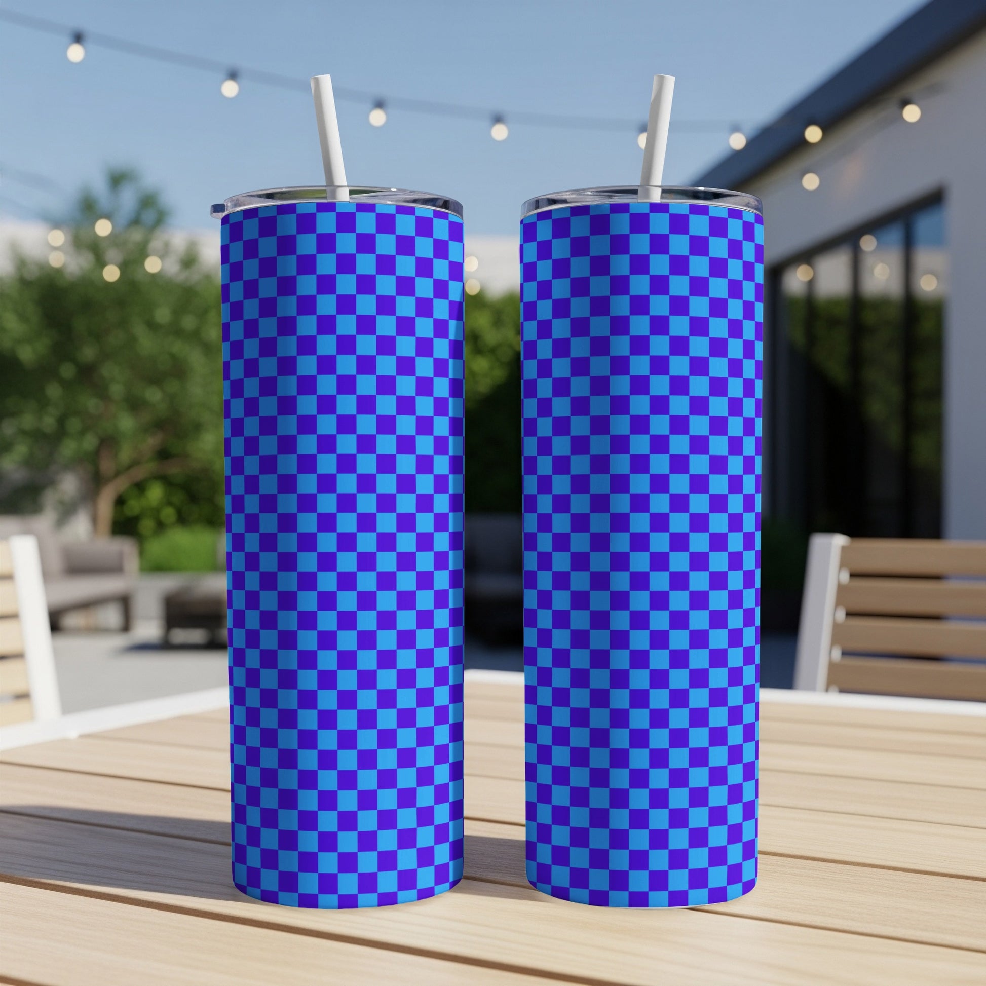 Two blue and purple checkered pattern tumblers with straws on a wooden table.