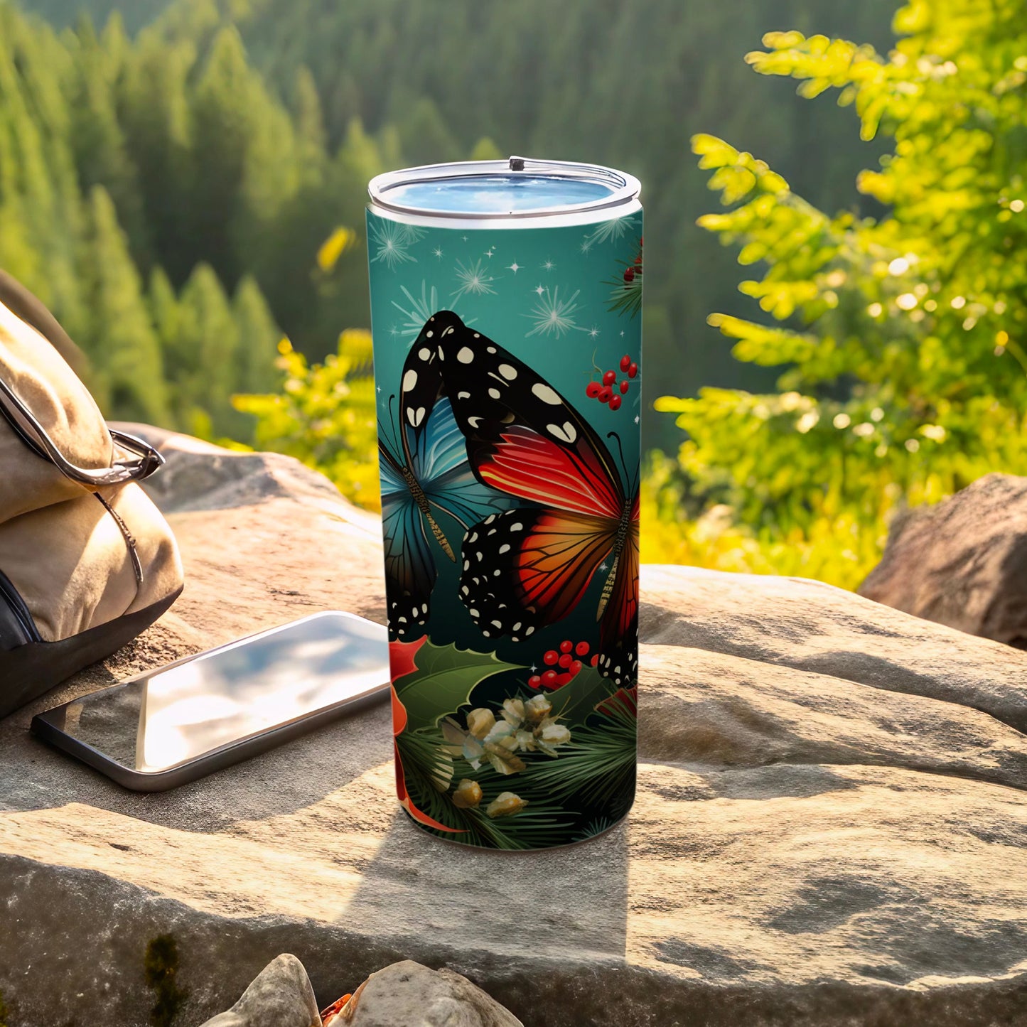 Butterfly design tumbler on a rock with a backpack and phone.