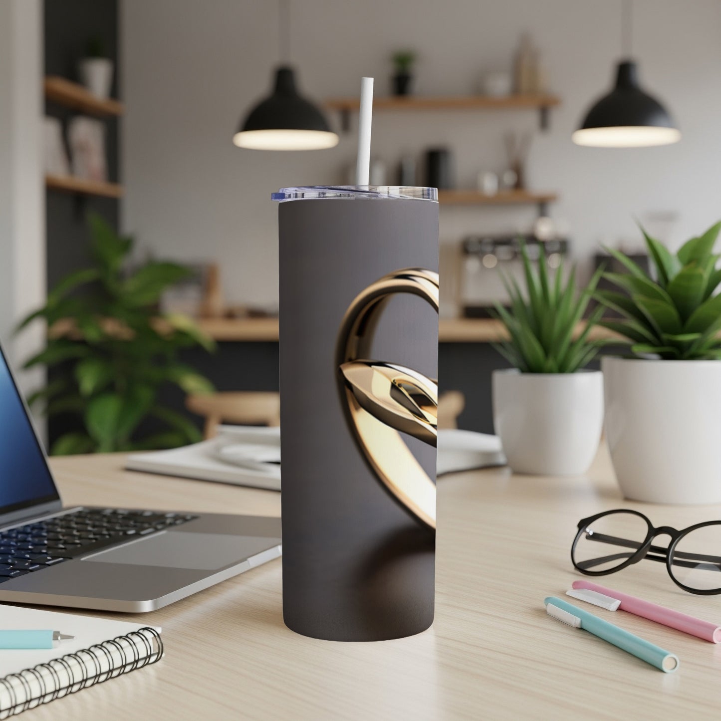 Black tumbler with a gold circular graphic and a straw.