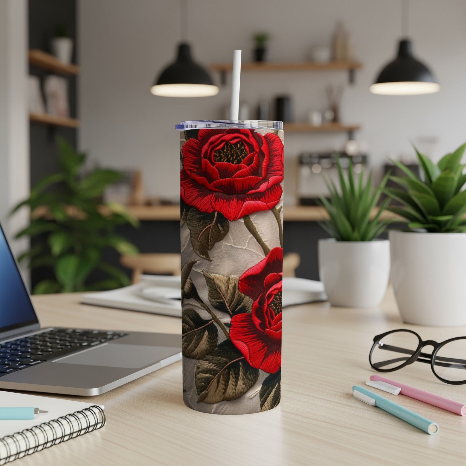Floral tumbler with red roses and textured background on desk.