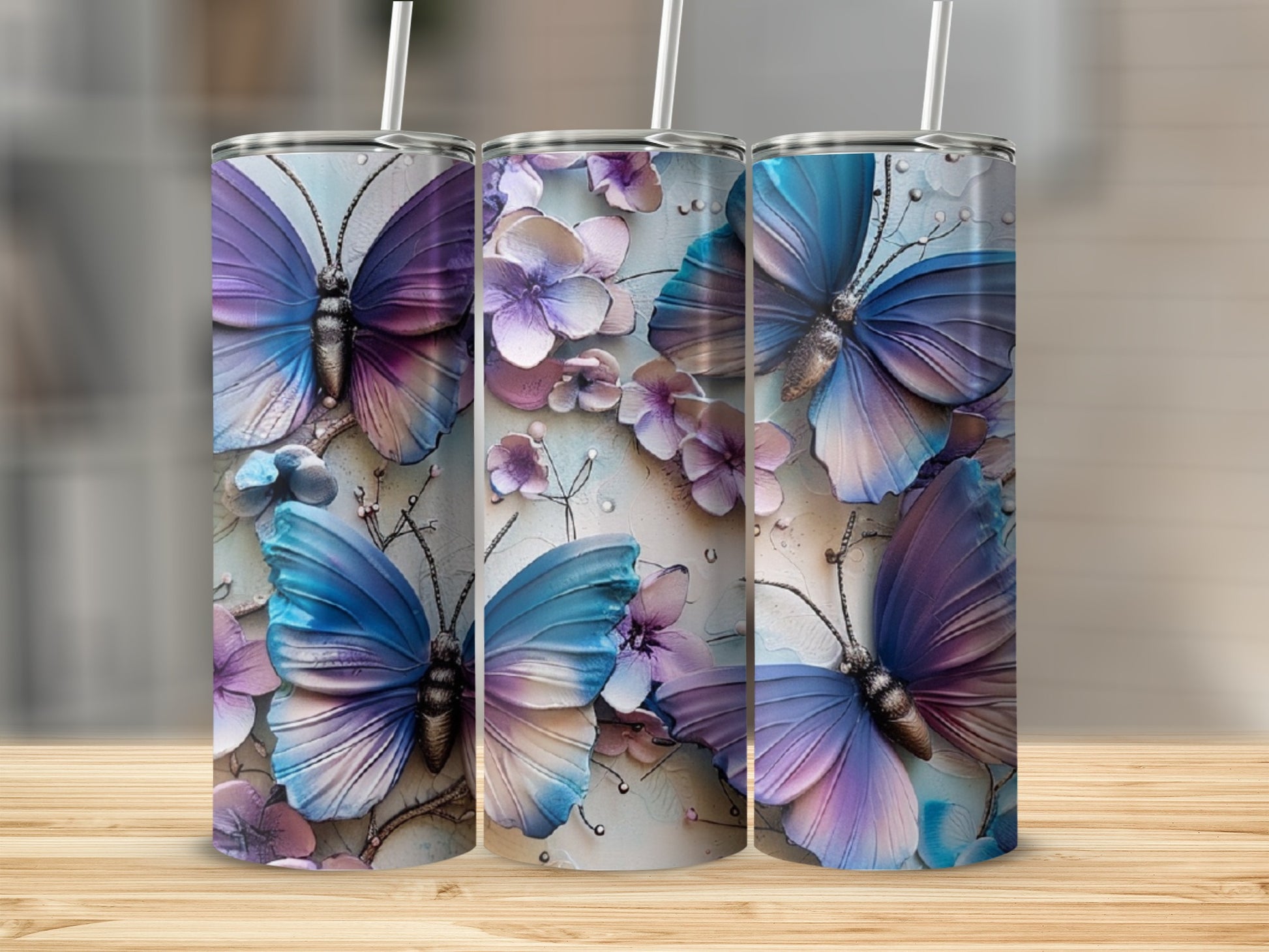 Three tumblers with colorful butterfly and floral designs.