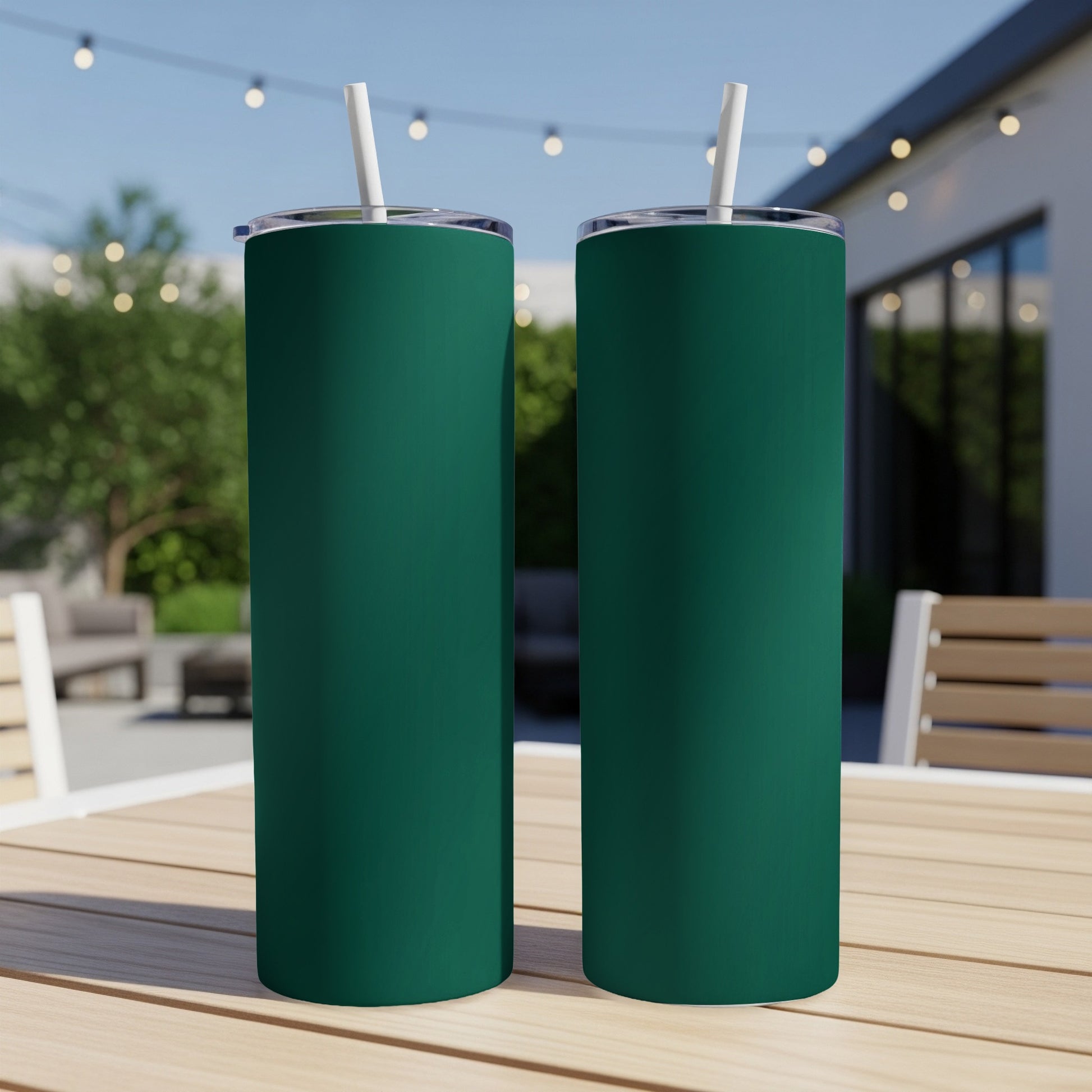 Two dark green tumblers with white straws stand on a wooden table.