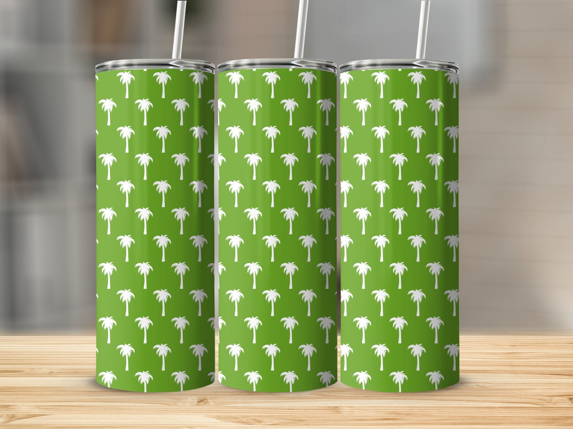 Three green tumblers with white palm tree pattern and straws.