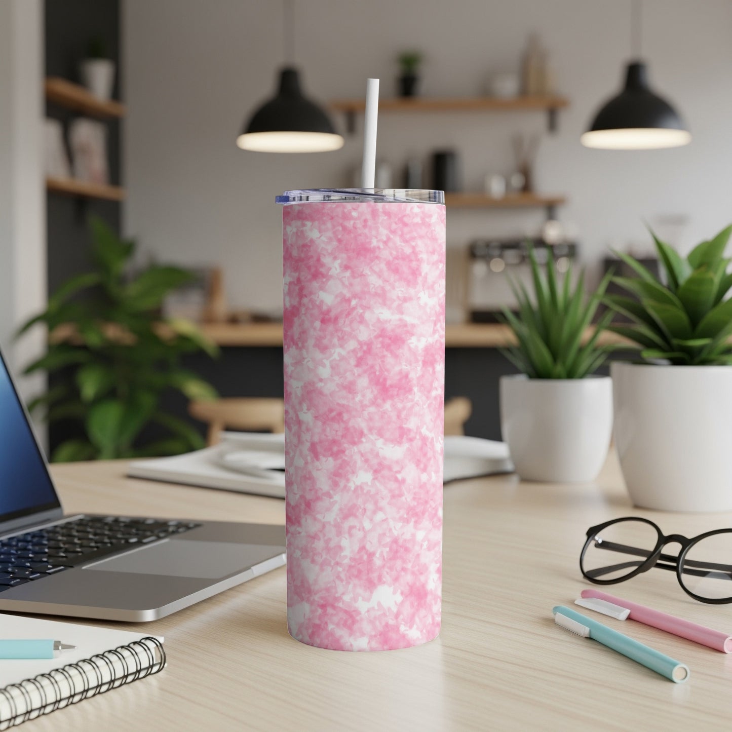 Pink marble print insulated tumbler with straw on a wooden desk.