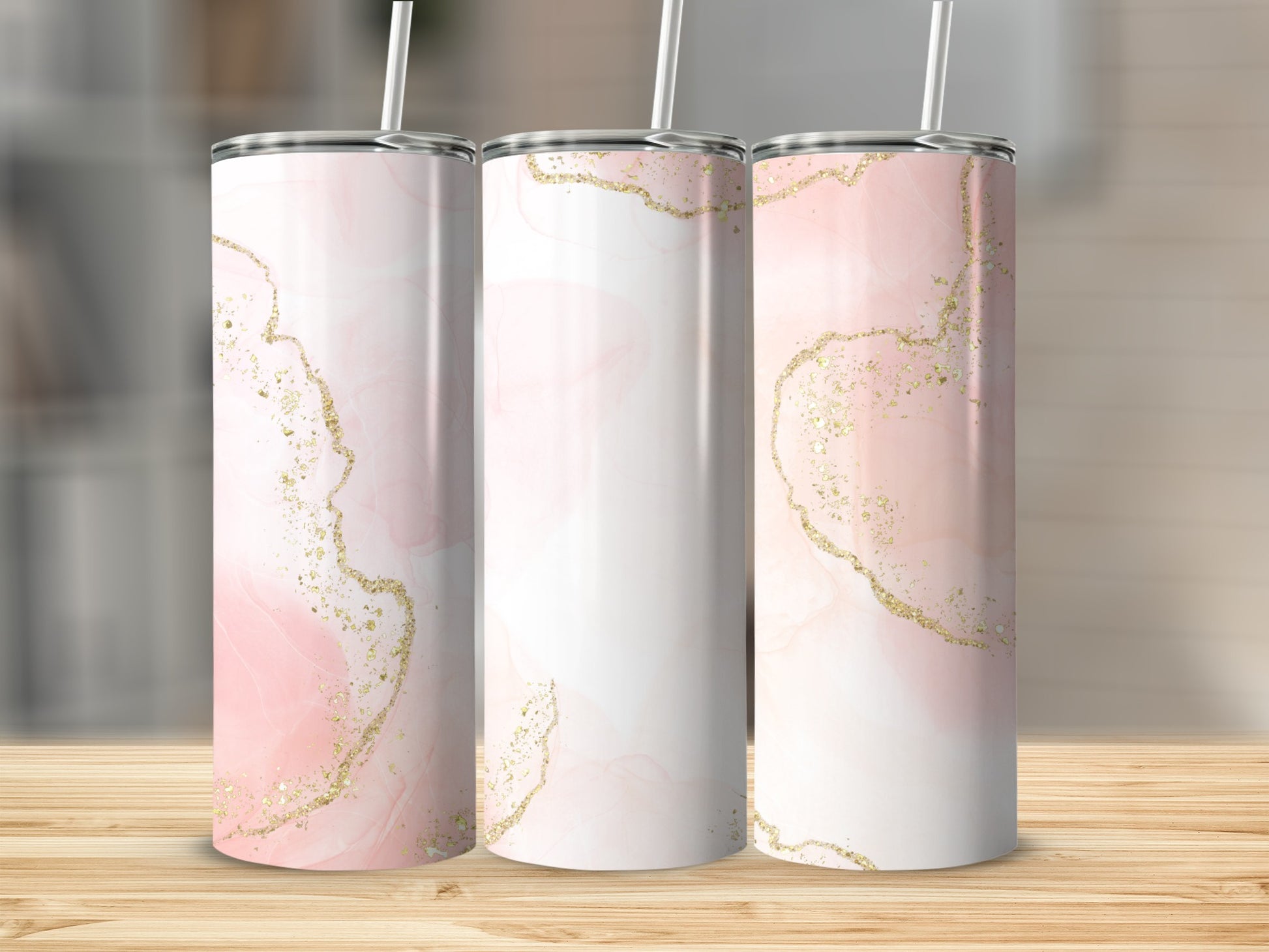 Three tumblers with pink marble and gold glitter designs on a wooden surface.