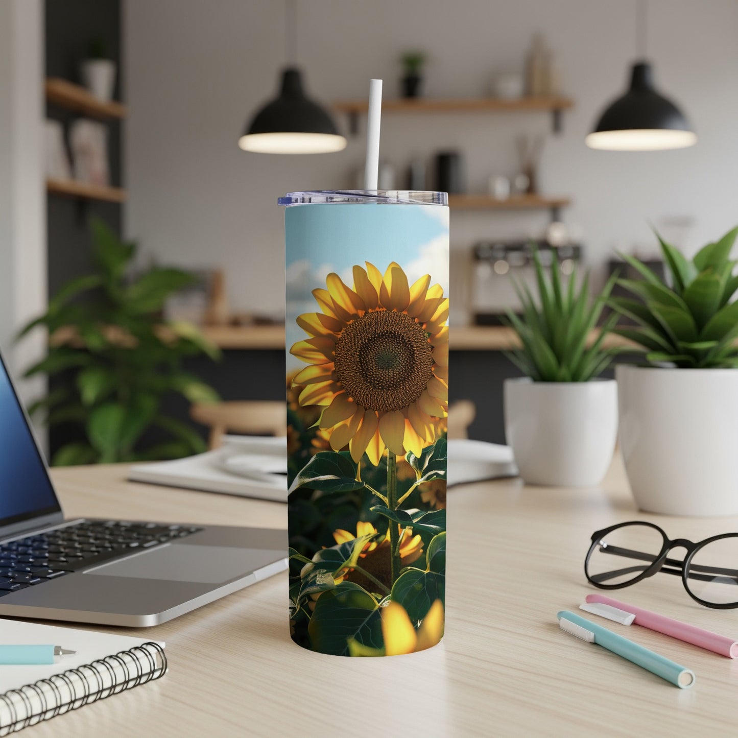 Sunflower on a tumbler, with a laptop and office supplies.