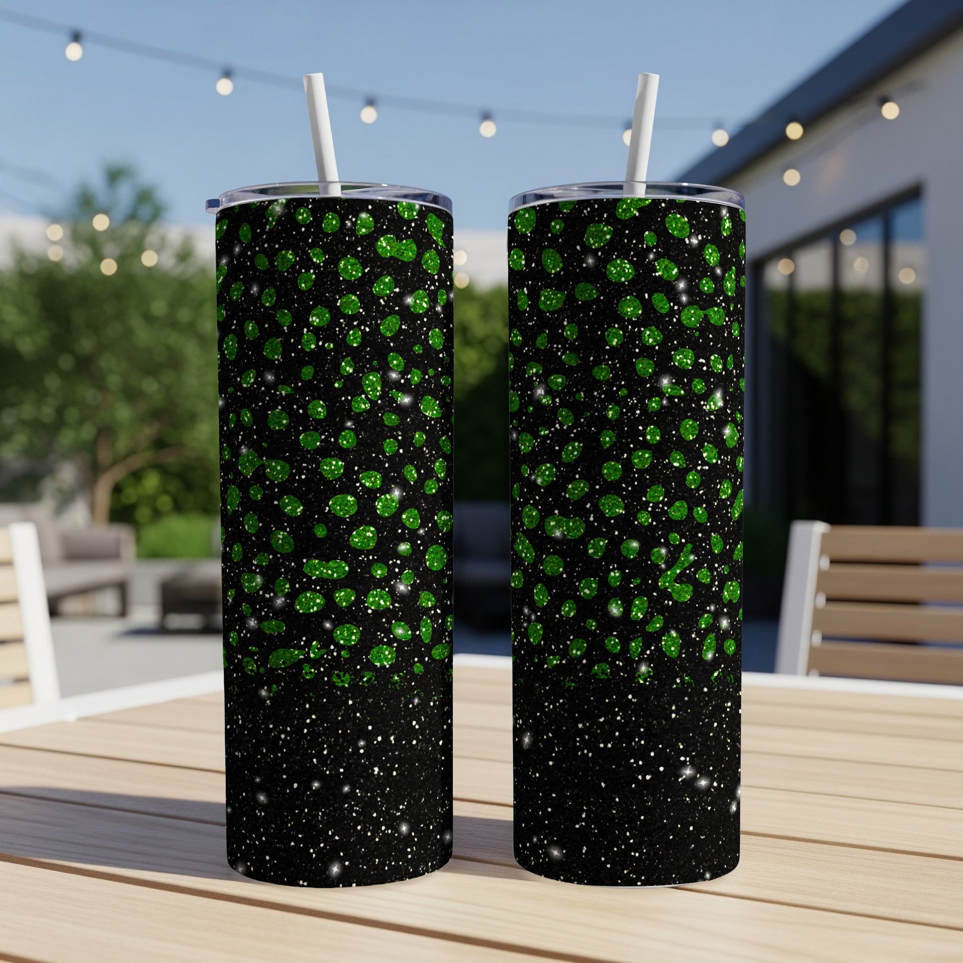 Two glittery green tumblers with straws on a wooden table.