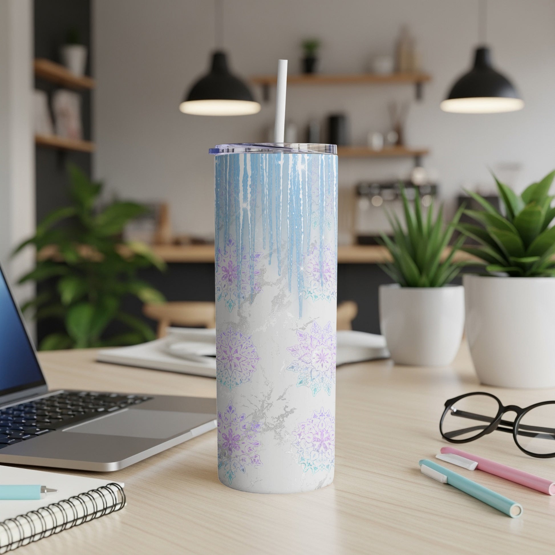 Blue and purple snowflake pattern tumbler with a white straw on a desk.