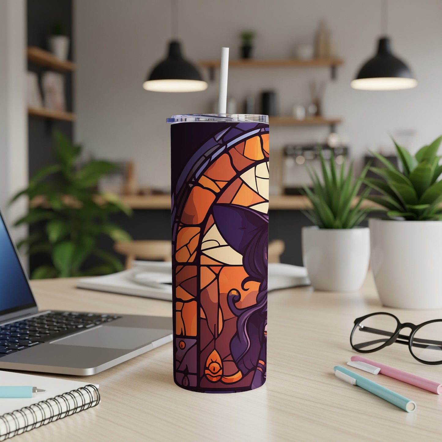 Purple tumbler with witch and stained-glass design on a desk.