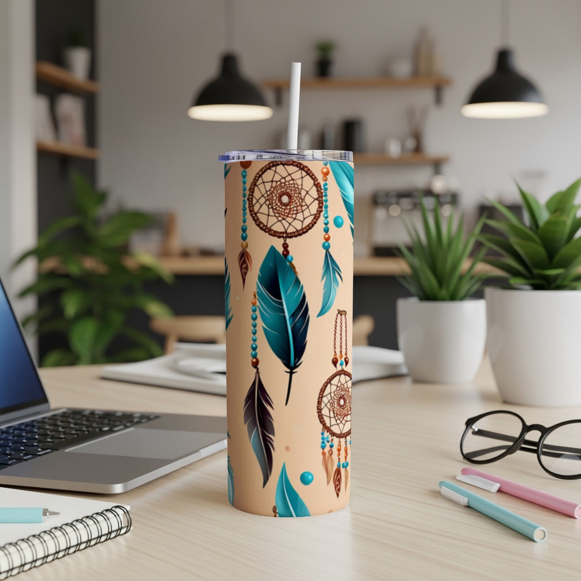 Beige tumbler with teal feathers and dreamcatchers, straw inserted.