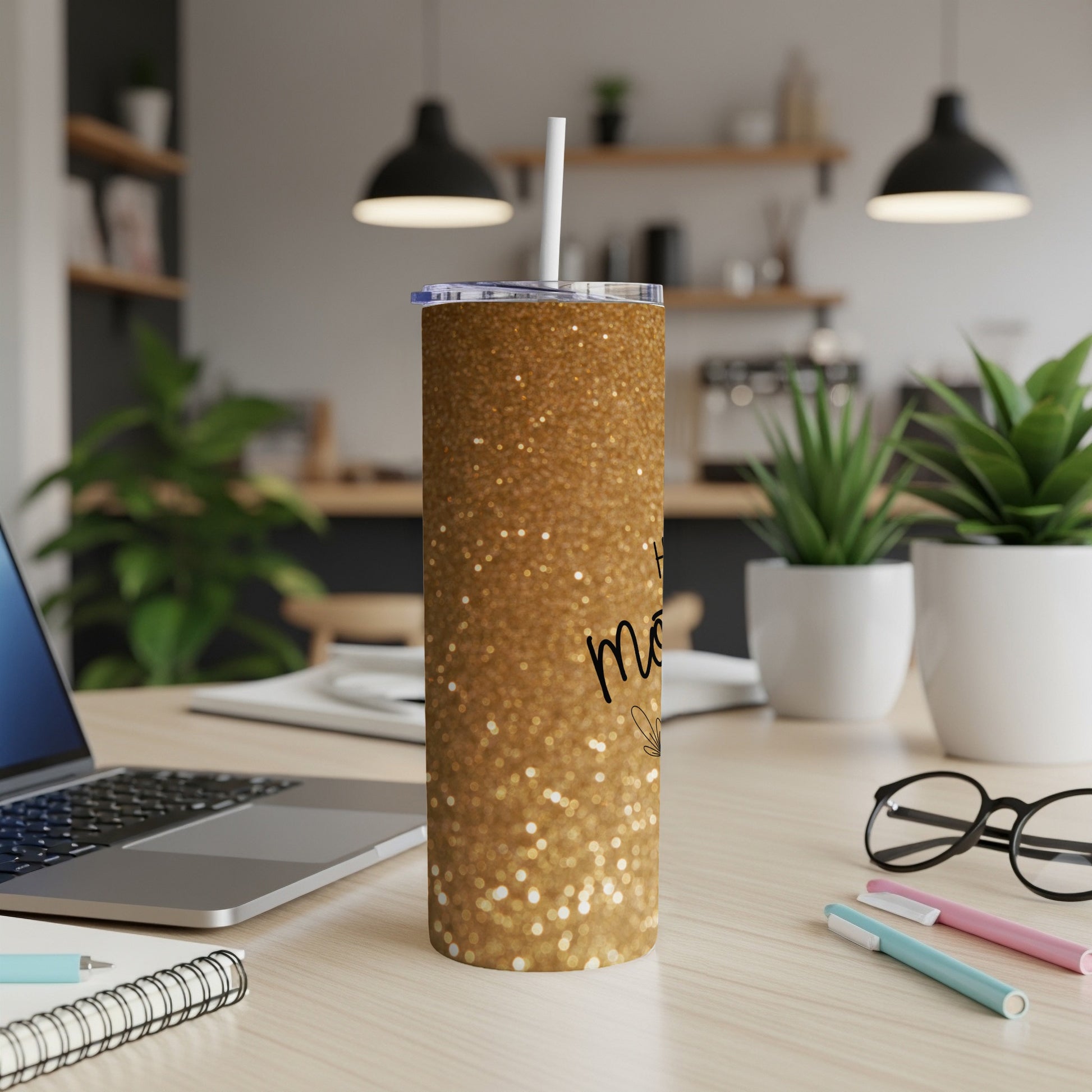 Gold glitter tumbler with "Mom" text on a desk with laptop.