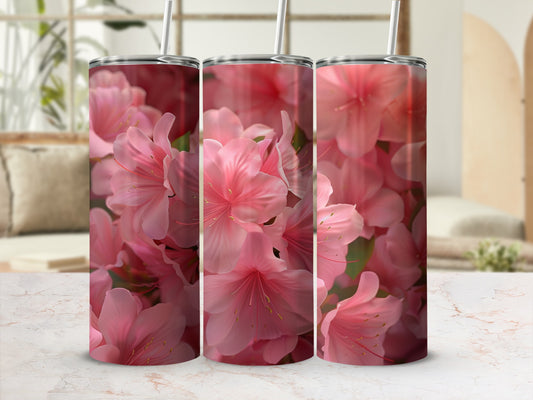 Three pink floral tumblers with straws on a marble surface.
