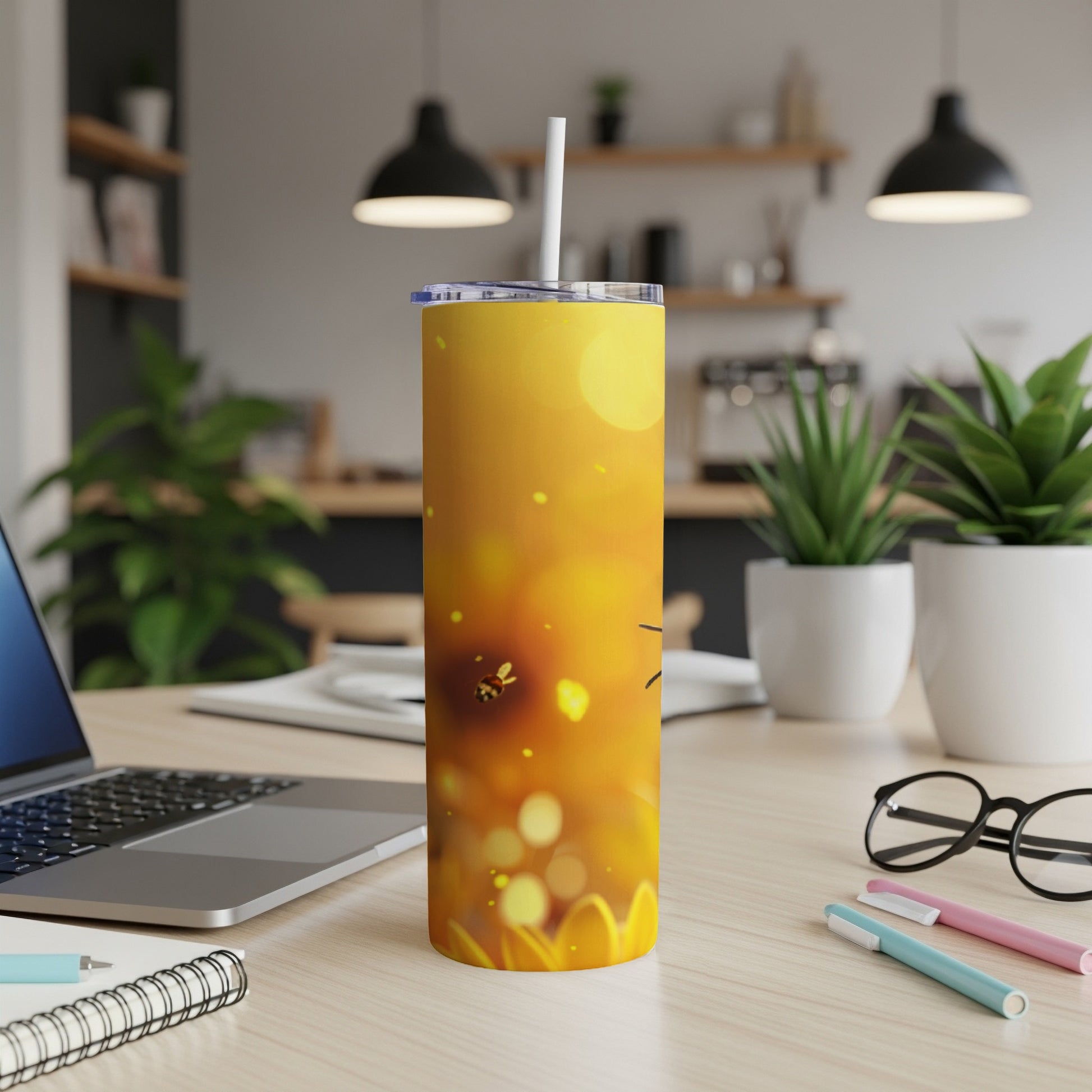 Yellow tumbler with bee and sunflower graphic on a desk.