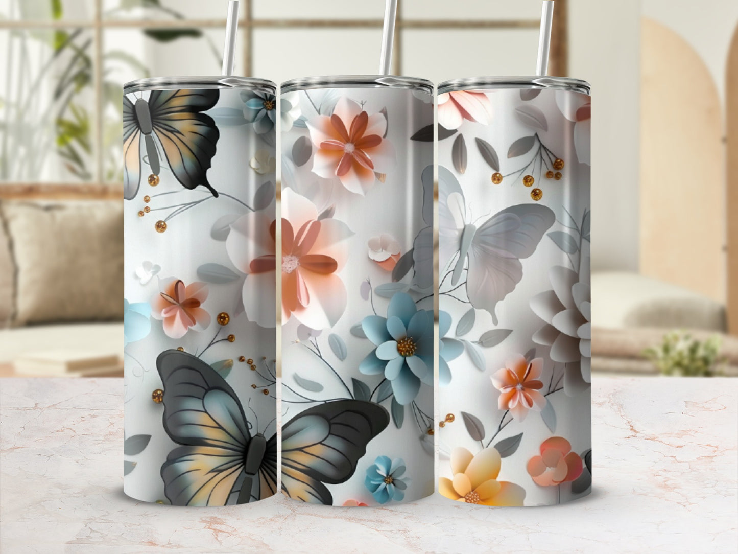 Three tumblers with butterflies and floral designs on a marble countertop.