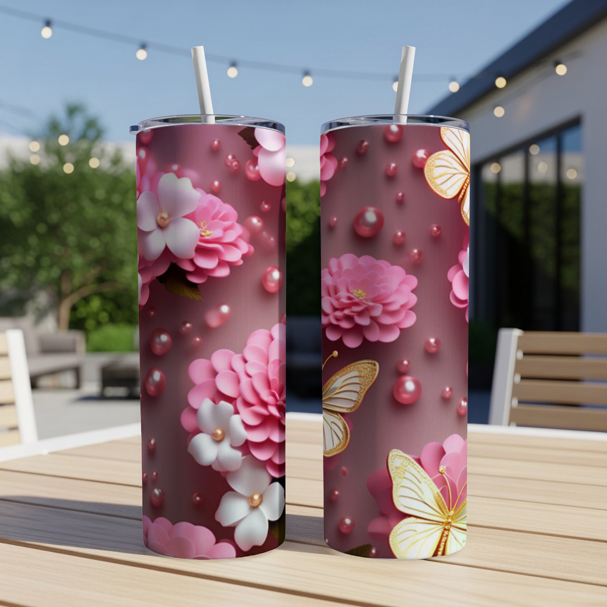 Two tumblers with pink flowers, white blossoms, and gold butterflies on a table.