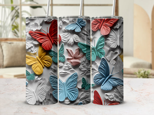 Three butterfly-patterned tumblers with straws on a marbled surface.