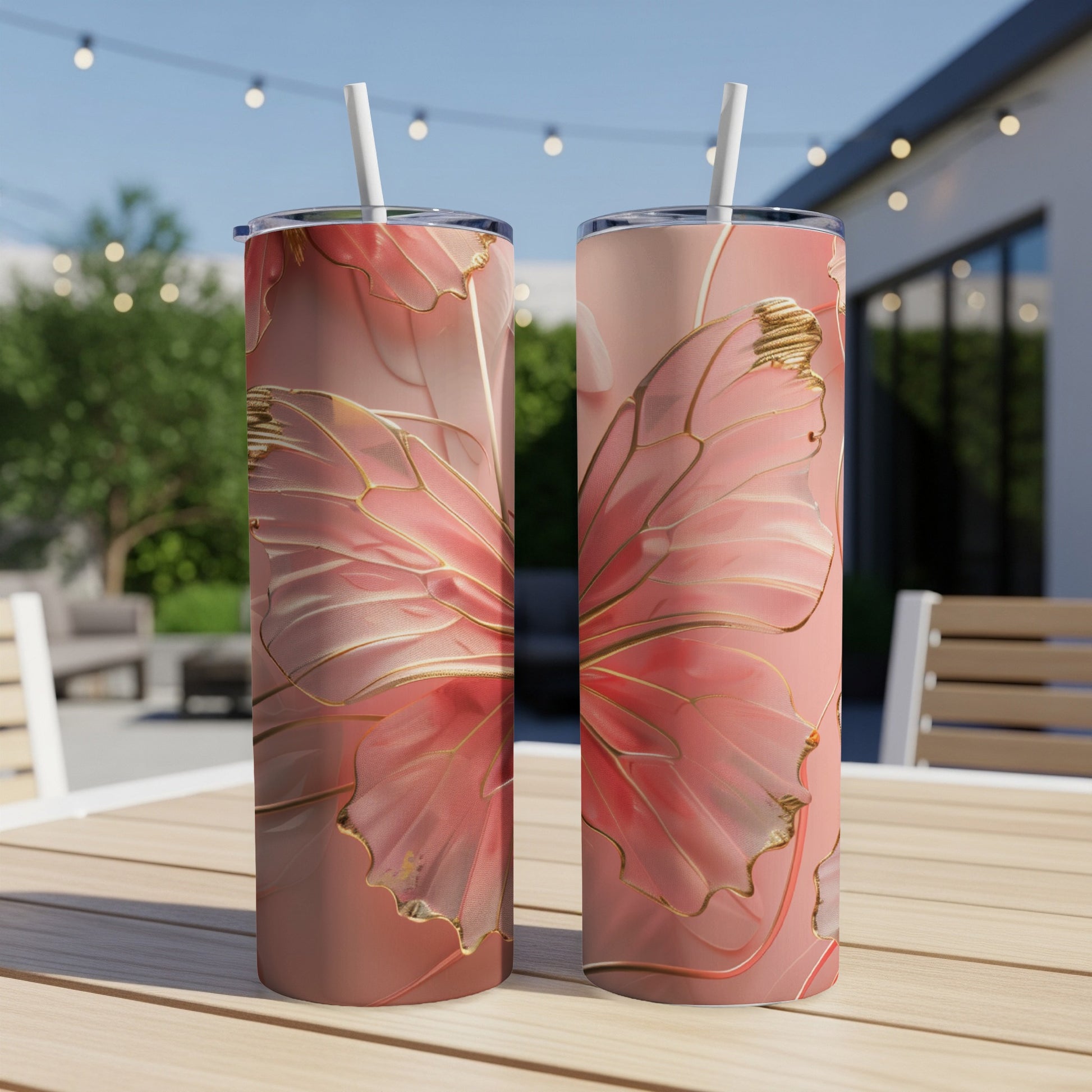 Two tumblers with a pink butterfly wing design and gold accents on a table.