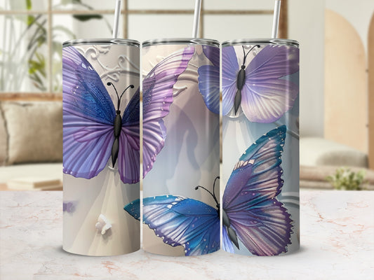 Three tumblers with purple and blue butterfly designs and white straws.