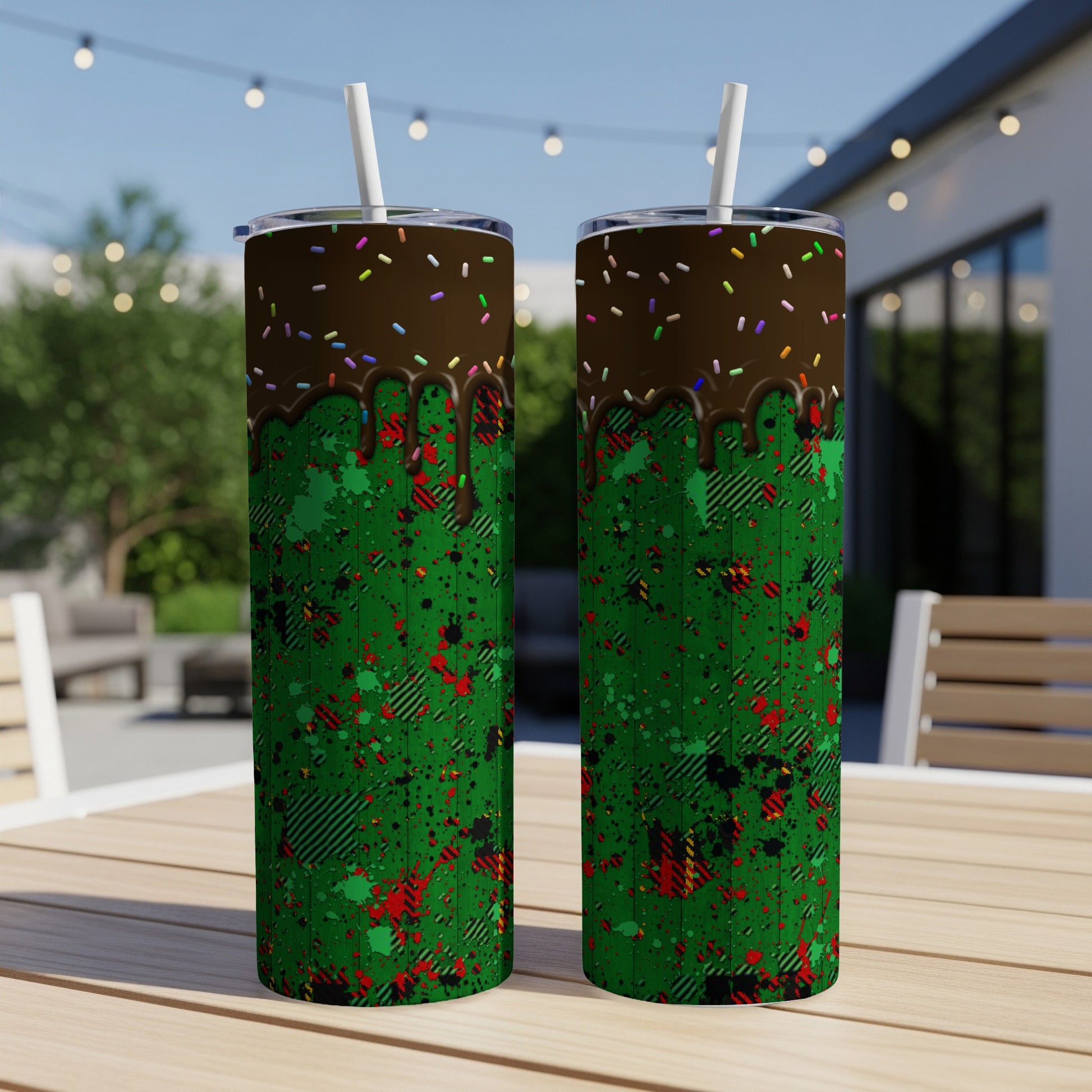 Two tumblers with chocolate drip and green splatter patterns sit on a table.
