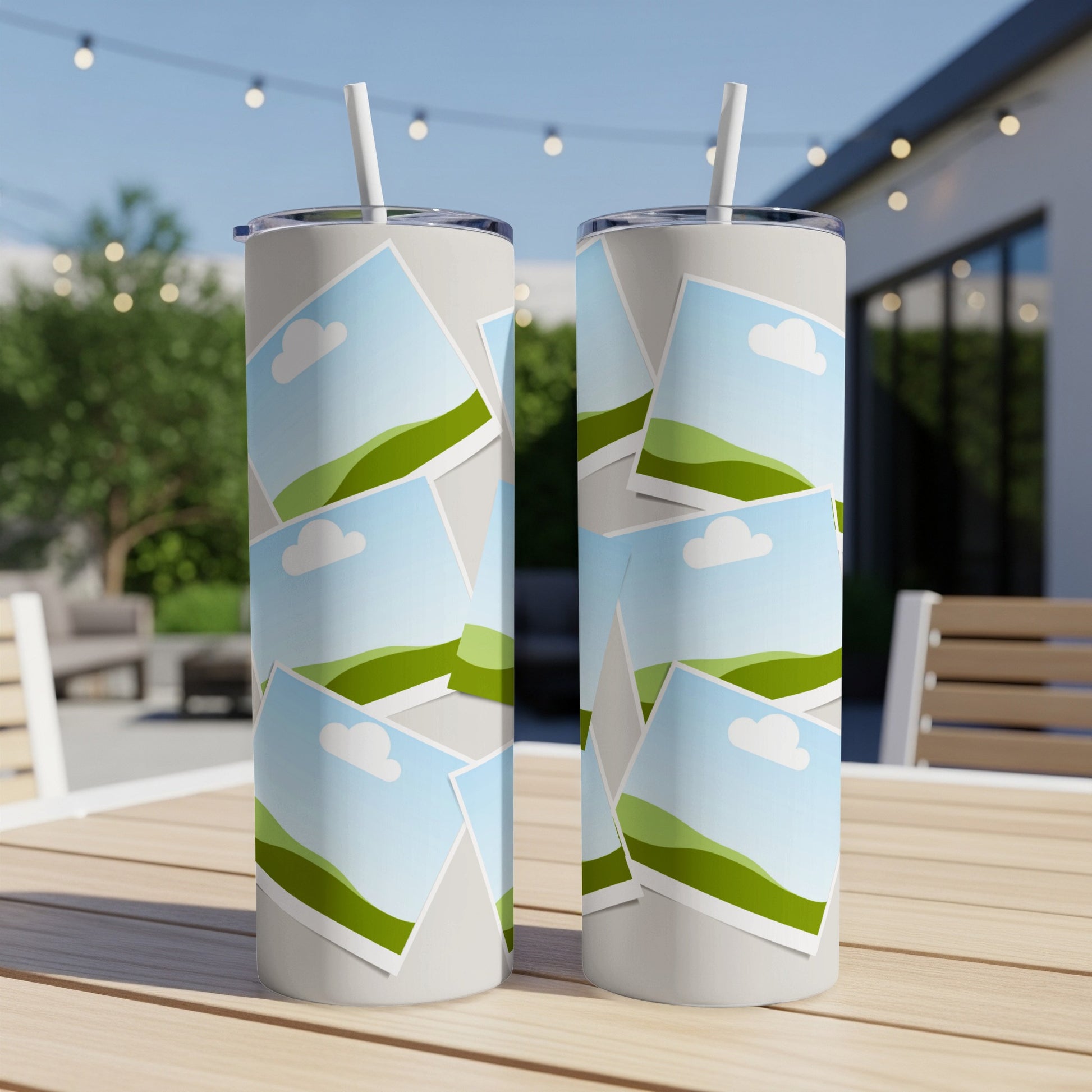 Two tumblers with a pattern of landscape photos on a wooden table.