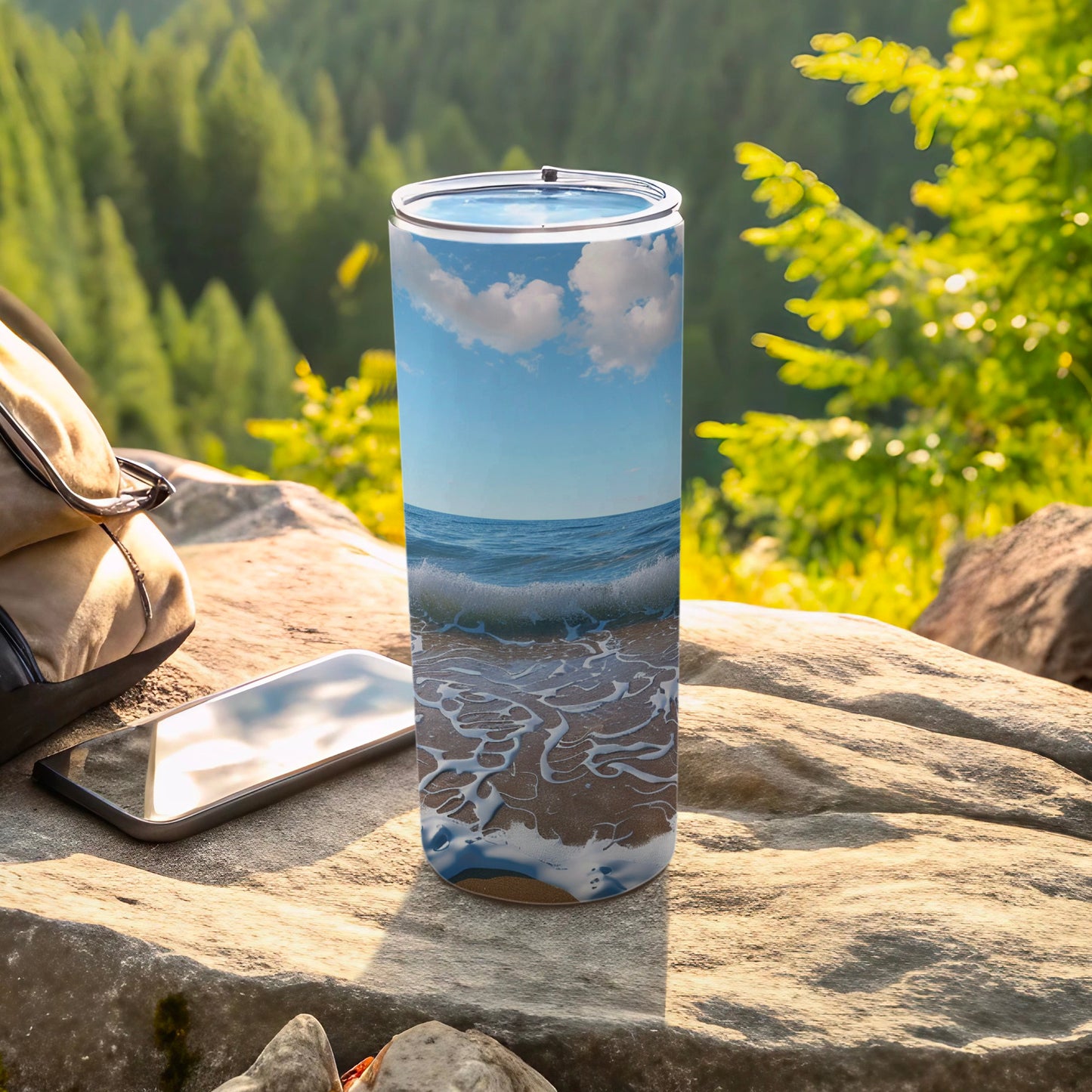 Tumbler with ocean waves and sky design on outdoor rocky surface.