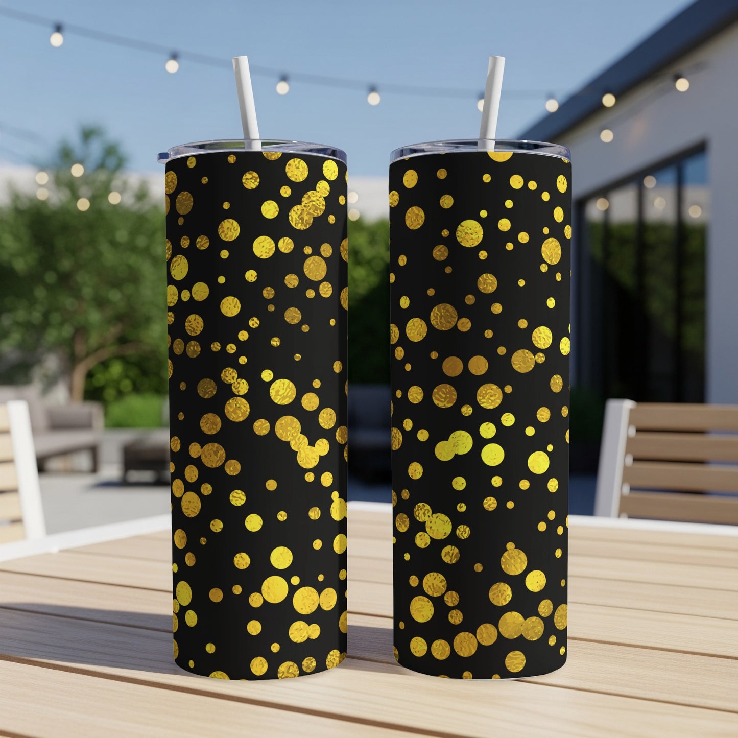 Two tumblers with black background and scattered gold dot pattern sit on a wood table.