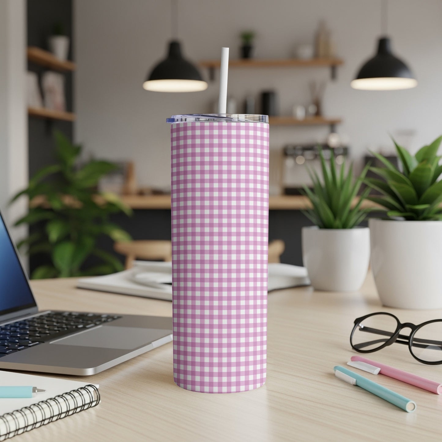 Pink and white gingham patterned tumbler with white straw on a wooden desk.
