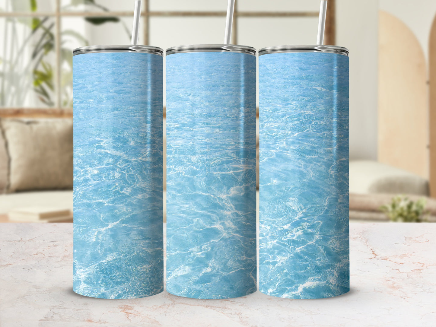 Three tumblers with rippling blue water design on a marble surface.