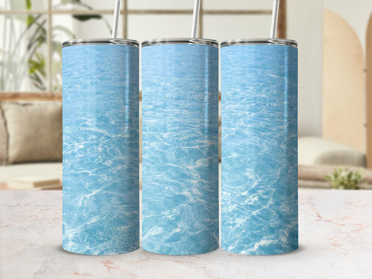 Three tumblers with rippling blue water design on a marble surface.