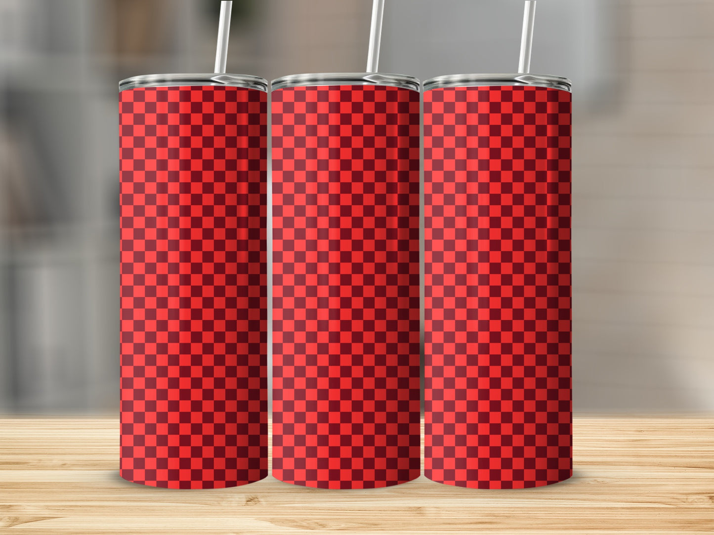 Three red and black checkered tumblers with straws on a wooden surface.