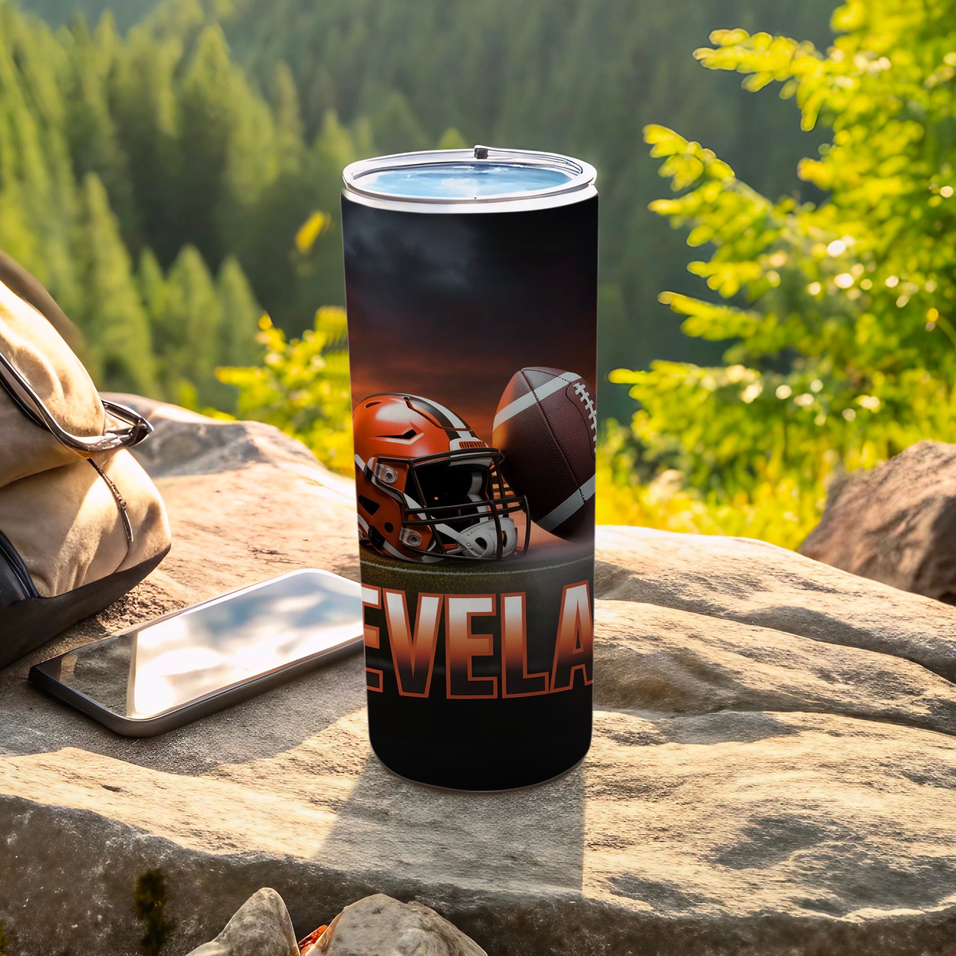 Tumbler with Cleveland football helmet and ball, outdoor setting.