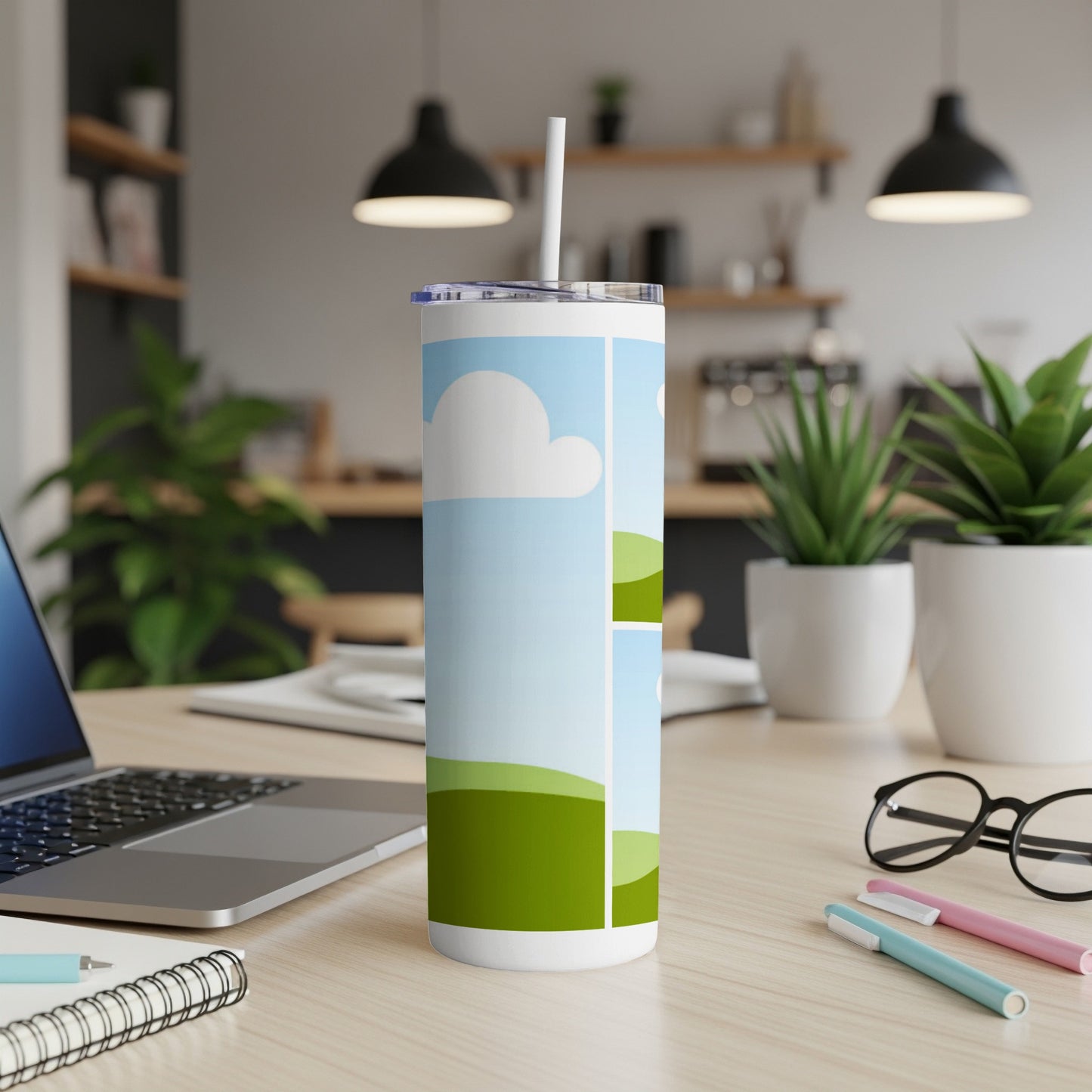 White tumbler with a cartoon landscape design, featuring clouds and green hills.