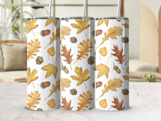Three tumblers with autumn leaf and acorn patterns on a table.