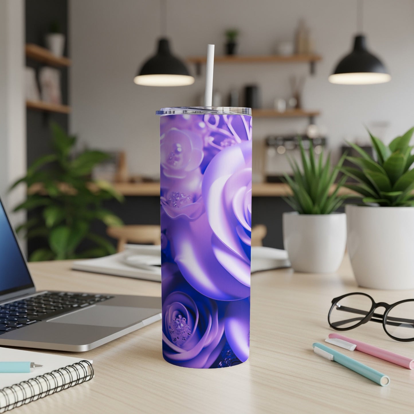 Purple roses wrap around a tumbler with a straw on a desk.