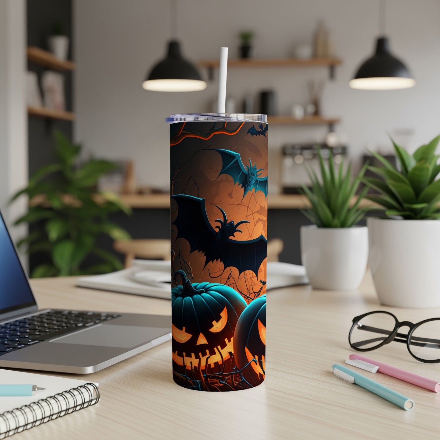 Halloween tumbler with jack-o'-lanterns and bats on a desk with a laptop.
