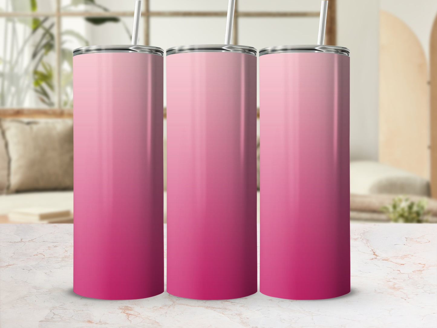 Three pink gradient stainless steel tumblers with straws on a marble surface.