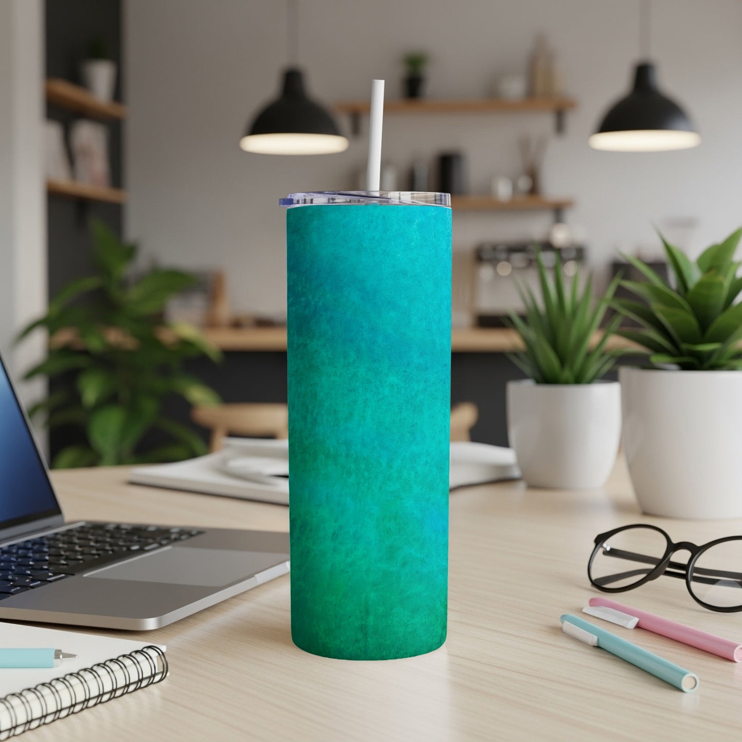 Turquoise and teal textured tumbler with a white straw on a desk.