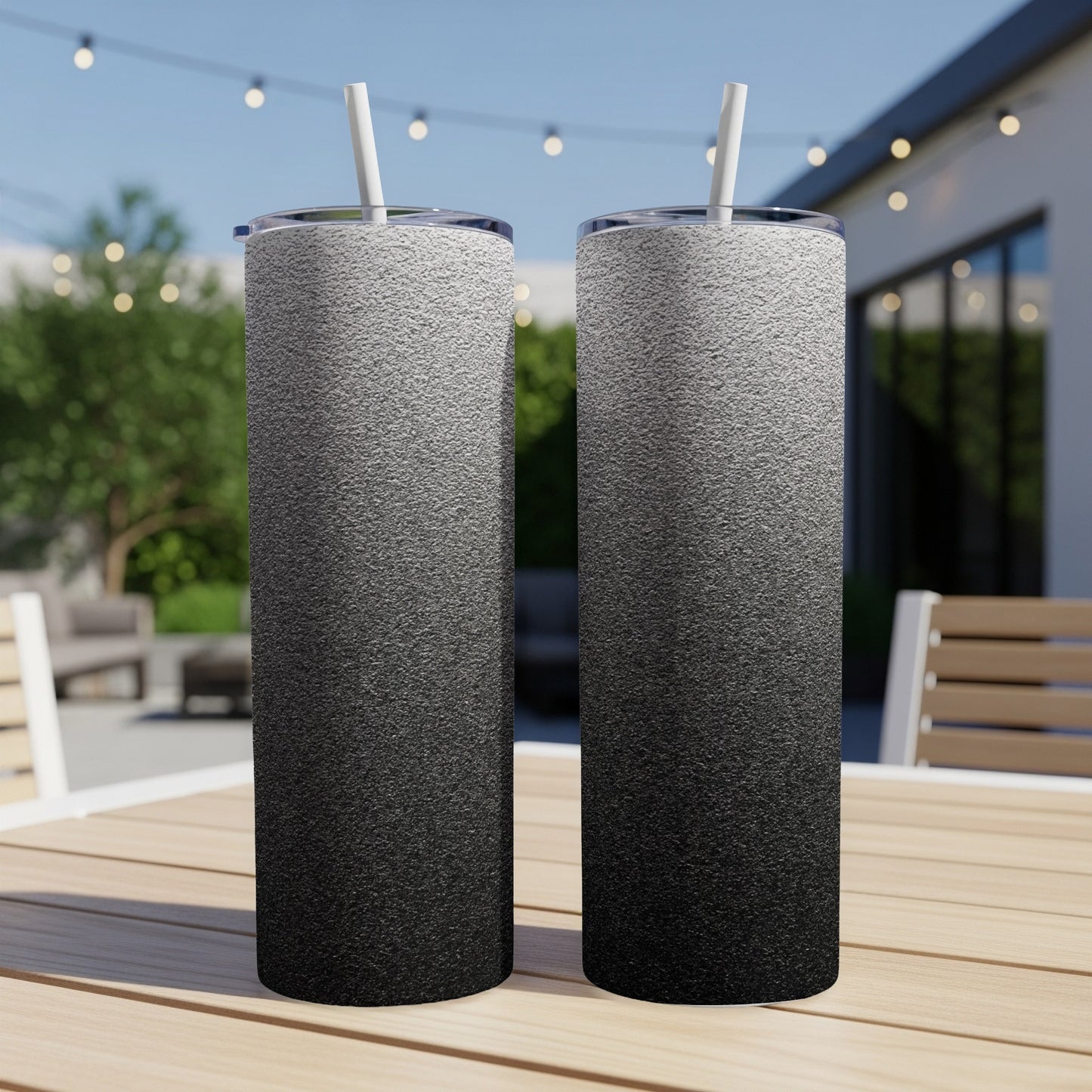 Two tall tumblers with a black to white gradient design on a wooden table.